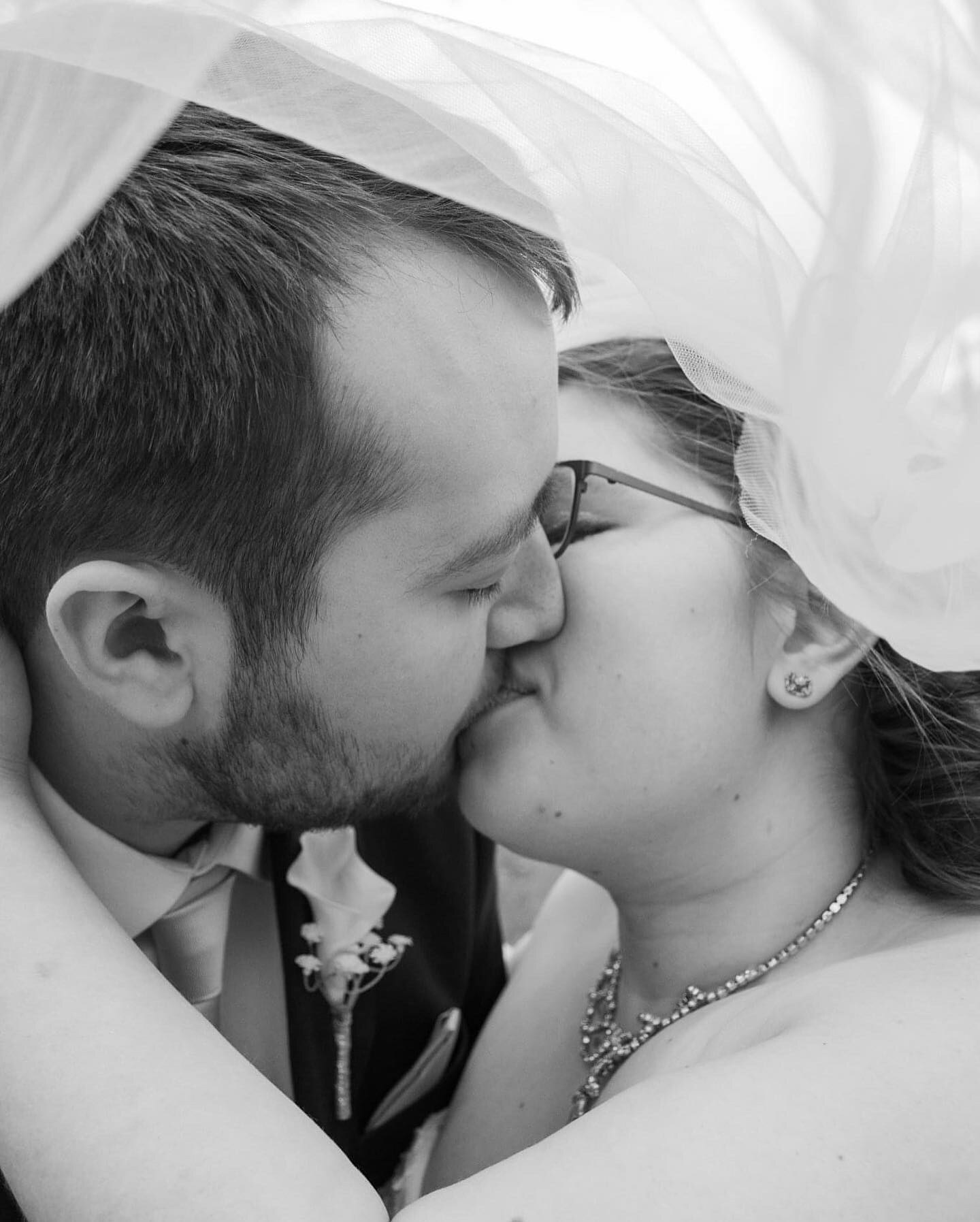 Black-and-white close portrait of a newly married couple kissing
