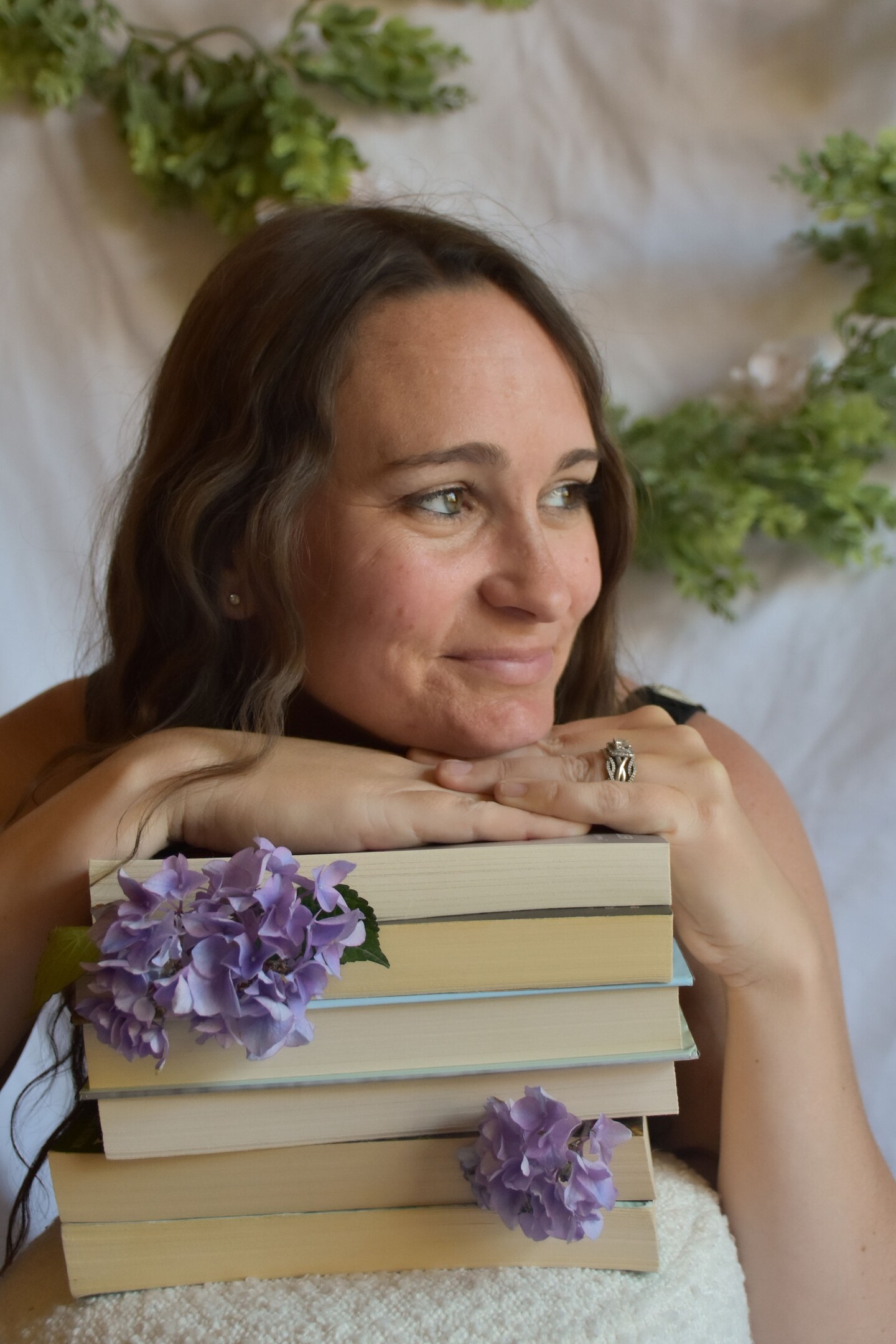 Woman resting her chin on a stack of books decorated with purple flowers