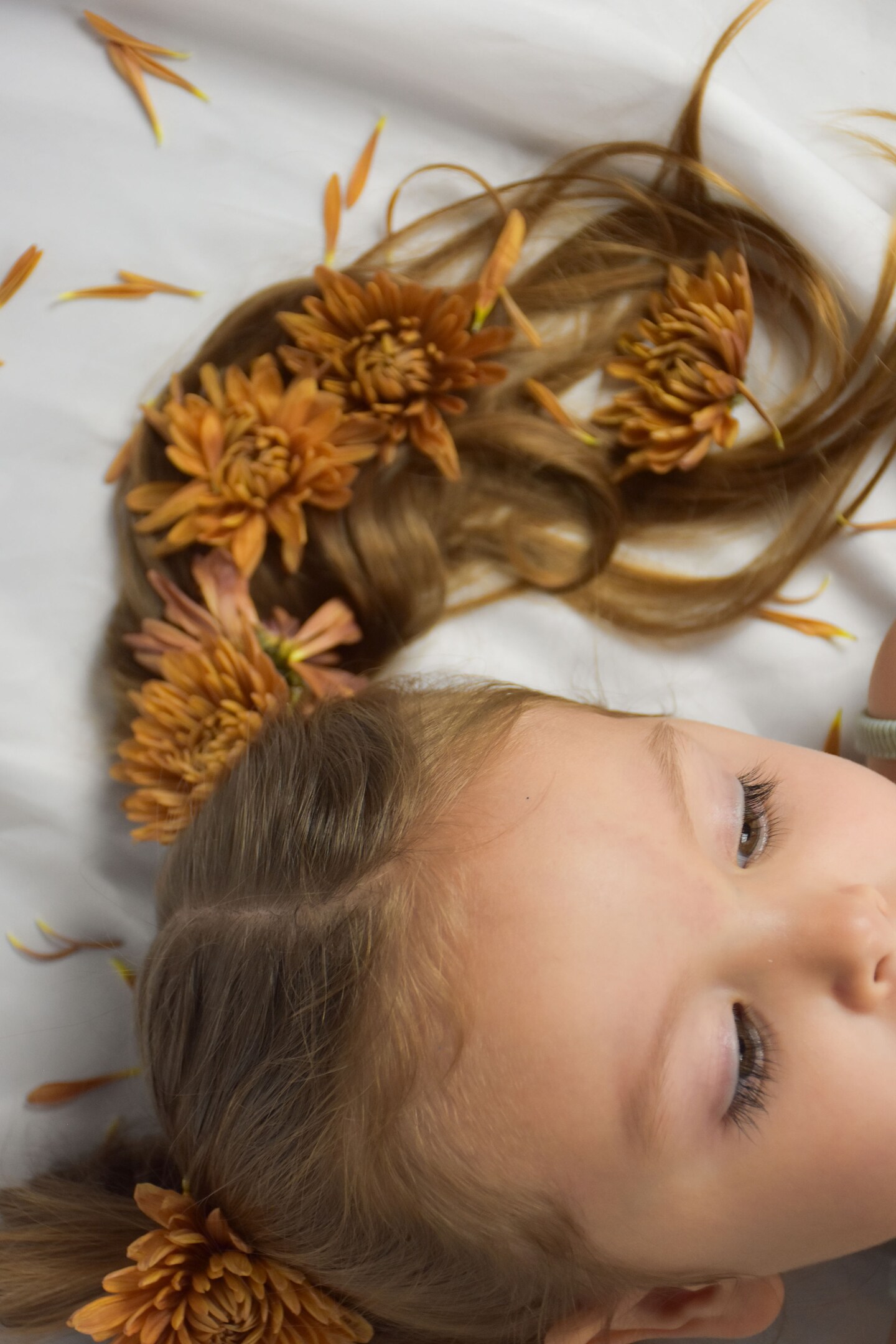 Young girl lying among warm-toned flowers