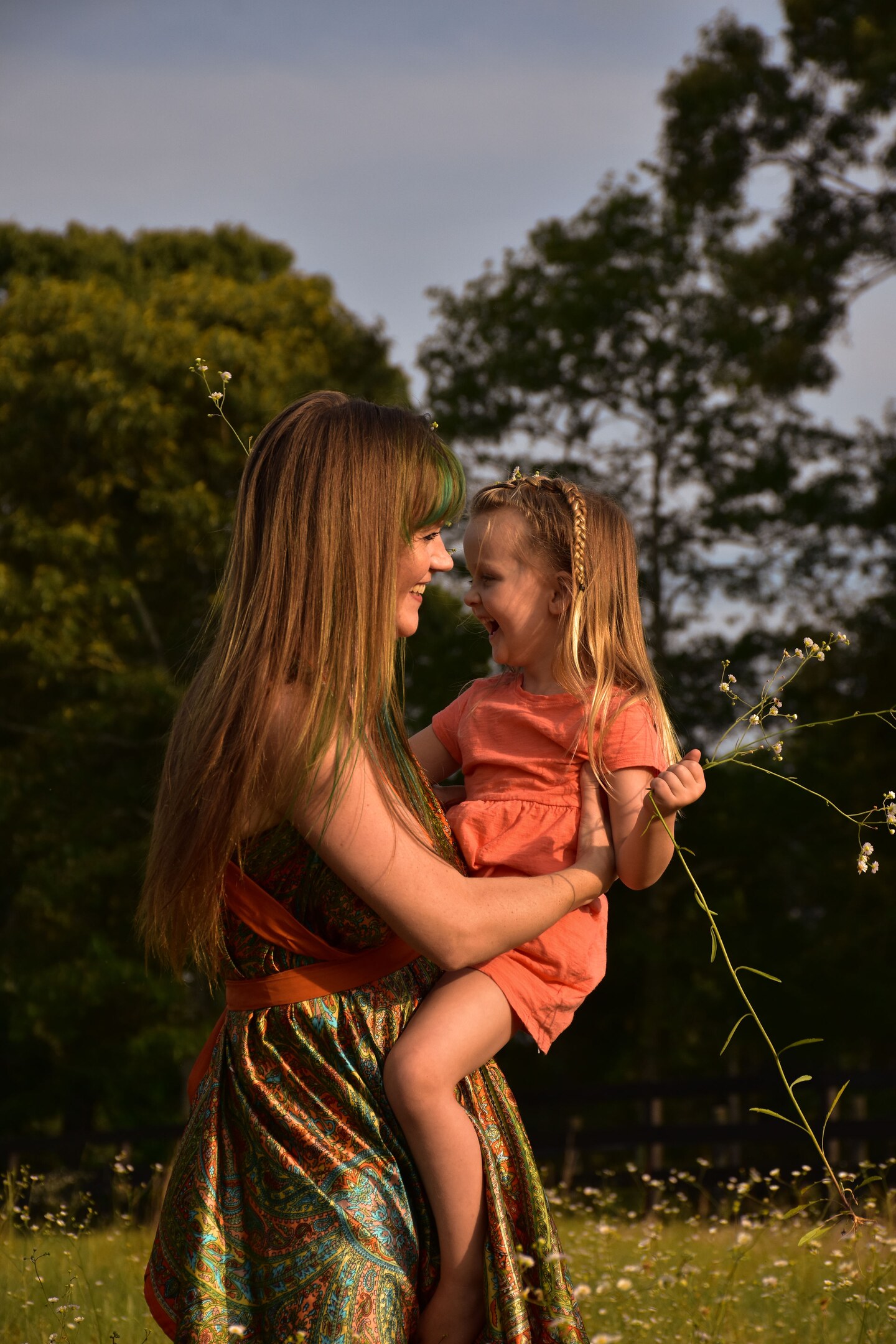 Mother holding her laughing young daughter in a wildflower field